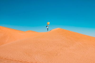 Low angle view of person in desert against clear blue sky