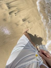 Low section of woman standing on sand at beach