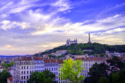 Buildings in city against cloudy sky