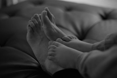 Low section of parent and child relaxing on bed at home