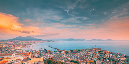 High angle view of townscape by sea against sky during sunset