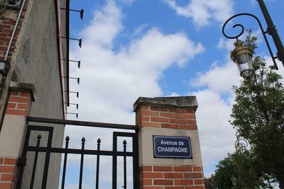 Low angle view of sign board against cloudy sky