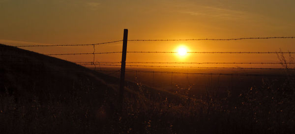 Silhouette field against sky during sunset