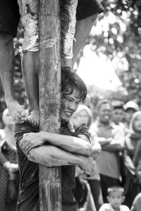 Close-up of man embracing pole while playing panjat pinang