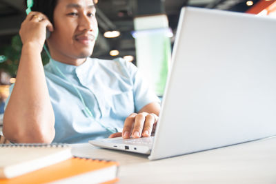 Midsection of man using mobile phone while sitting on table