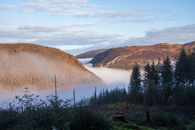 Scenic view of landscape and mountains against sky with a valley covered by low clouds 