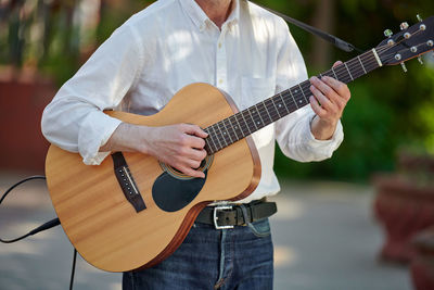 Midsection of man playing guitar