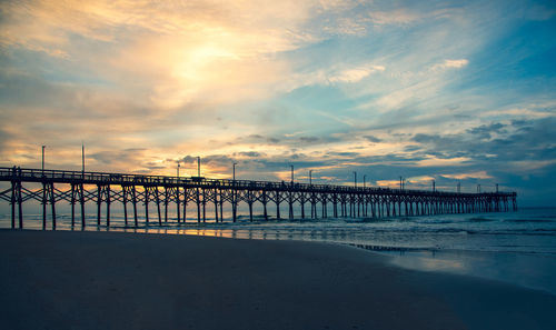 Pier over sea against sky during sunset