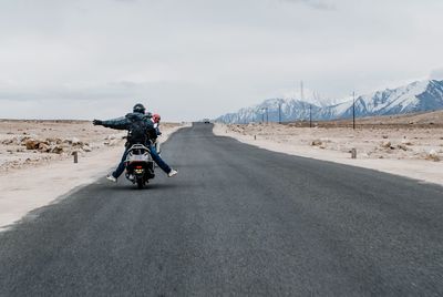 Man riding motorcycle on road against sky