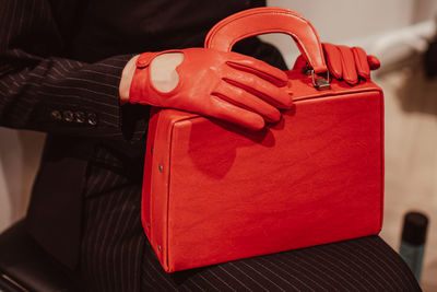 Female hands in a leather gloves holding a classic bright red handbag. fashion shot