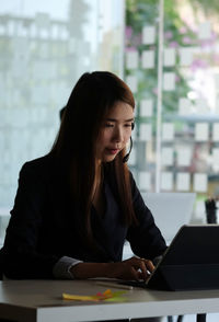 Young woman looking at camera while sitting on table