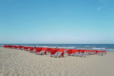 Deck chairs on beach against blue sky