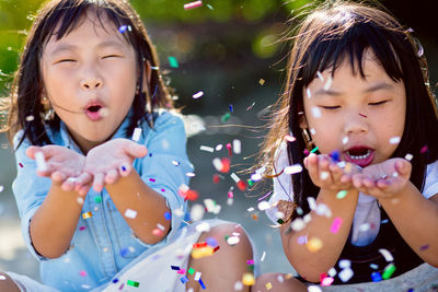 Close-up of girls blowing confetti