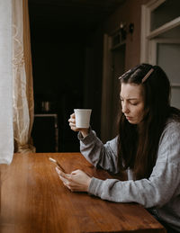 Young woman using mobile phone on table
