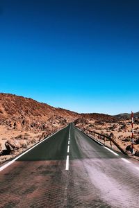 Road against clear blue sky