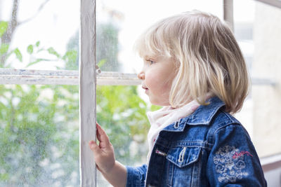 Side view of woman looking through window