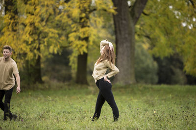 Young couple dancing on grassy field at park