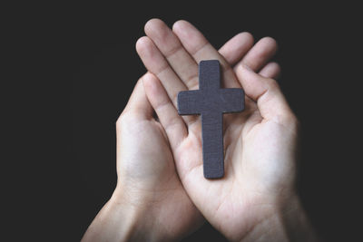 Close-up of hand holding toy over black background