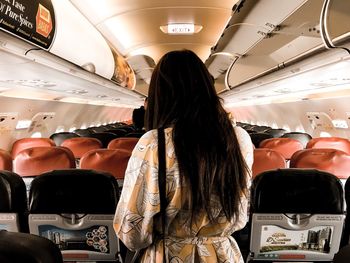 Rear view of woman sitting in airplane
