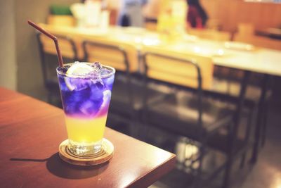 Purple and yellow colour herbal juice iced drink on restaurant brown wooden table.