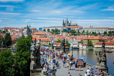 High angle view of people walking on bridge over river by buildings against sky