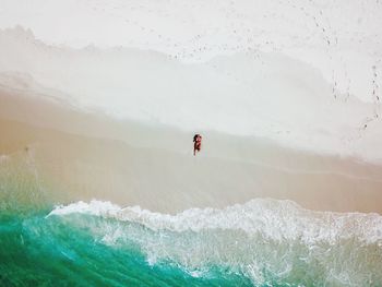 Directly above aerial view of woman sunbathing on shore at beach