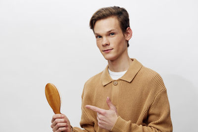 Portrait of young man holding globe against white background