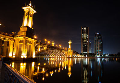 Illuminated bridge over river at night