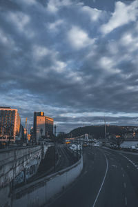 Highway in city against sky at sunset