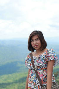 Beautiful young woman standing against sky