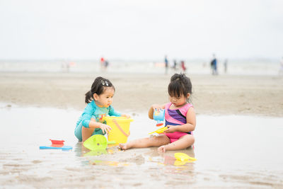 Cute sisters playing with toys on beach