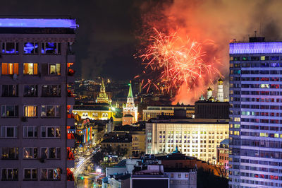 Firework display over illuminated buildings in city