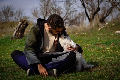 Woman with dog sitting on field