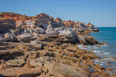 Rock formation on beach against clear blue sky