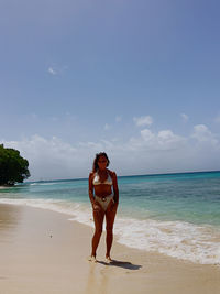 Full length of woman standing at beach against sky