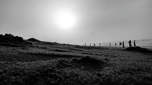 Surface level shot of silhouette people at beach against clear sky