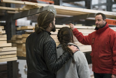 Salesman assisting couple with wooden planks in hardware store