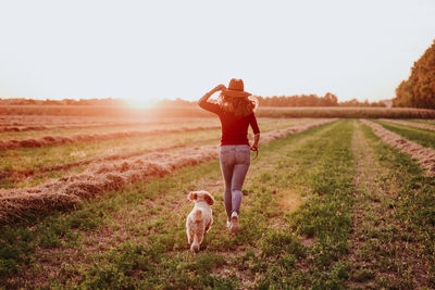 Rear view of woman running with dog on land