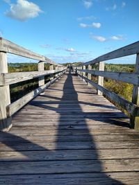 Wooden footbridge on footpath against sky