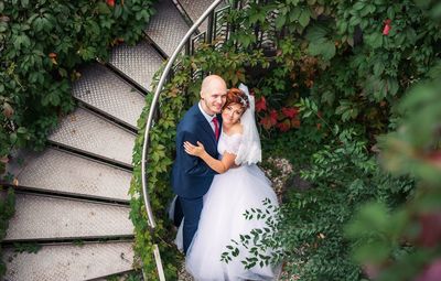 High angle portrait of bridal couple embracing by staircase at park