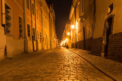 Illuminated street amidst buildings at night