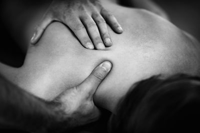 Close up image of physical therapist massaging female clients shoulder.