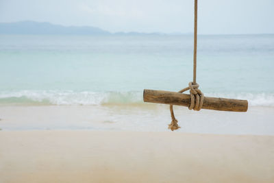 Wooden logs with rope hanging on the tree at beautiful beach with gorgeous sea and mountain view 