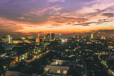 Aerial view of illuminated buildings against cloudy sky at sunset