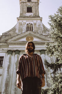 Portrait of young man standing against church