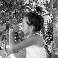 Side view of cute boy standing by plants