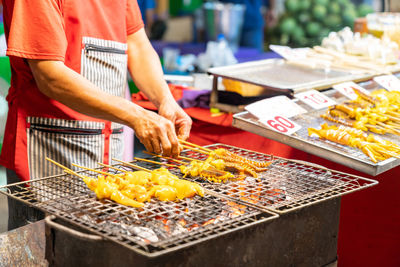 The man grilled squid and flip on chracoal grill at street food market.