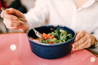 Happy young vegetarian woman eats healthy vegan food green salad sitting in a restaurant