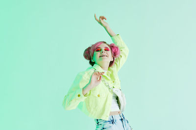 Low angle view of girl with arms raised standing against blue background