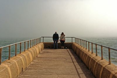 Rear view of woman standing on jetty